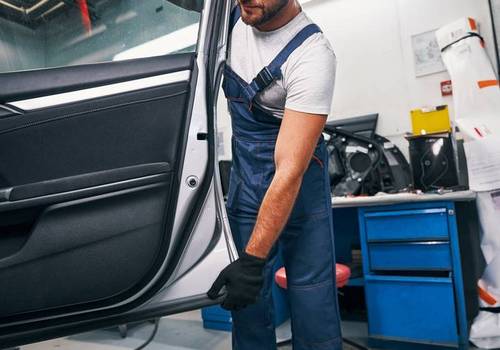 Mechanic taking off a door of automobile